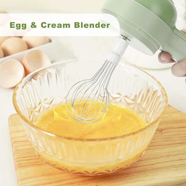 Green electric food cutter using whisk attachment to blend eggs in a glass bowl on wooden board