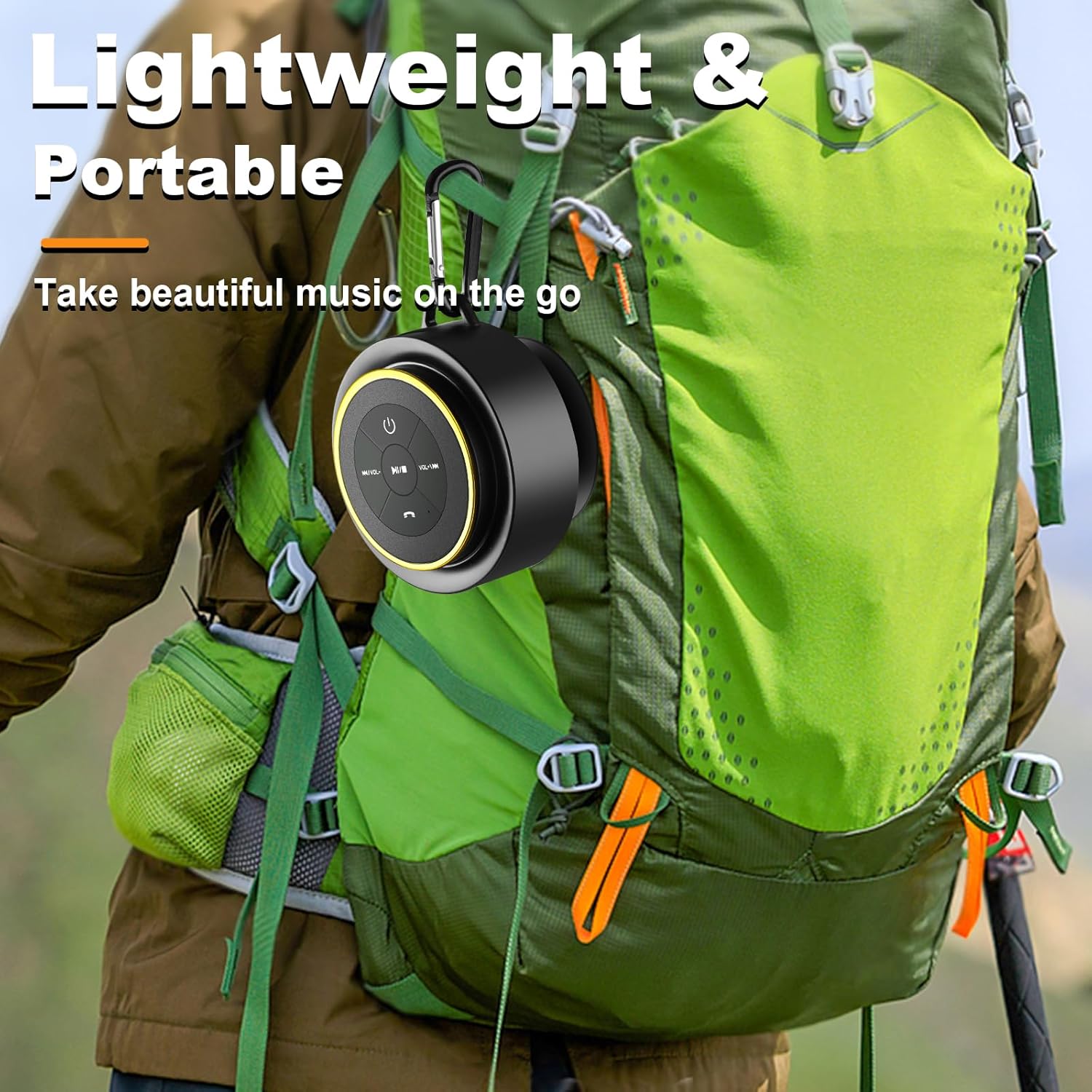 A black and gold mini Bluetooth speaker attached via carabiner clip to the side of a green hiking backpack worn by an outdoor hiker