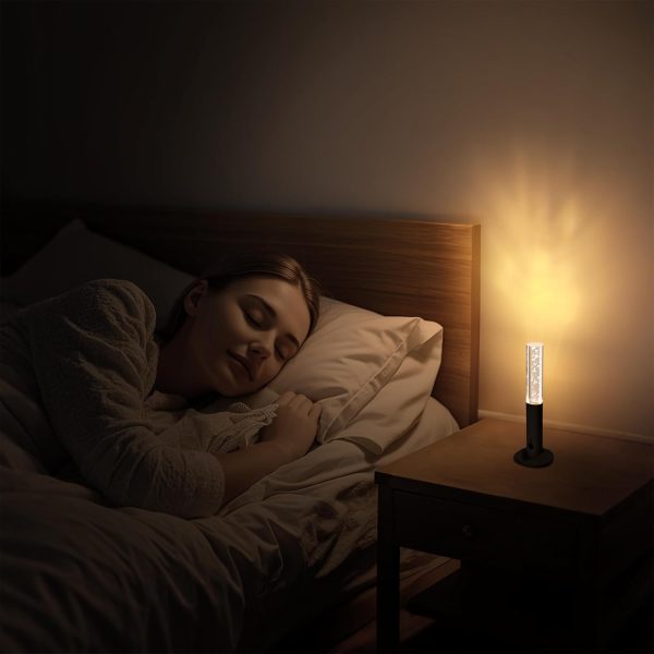Woman sleeping peacefully in a dark bedroom with a warm glowing wooden night light placed on the bedside table